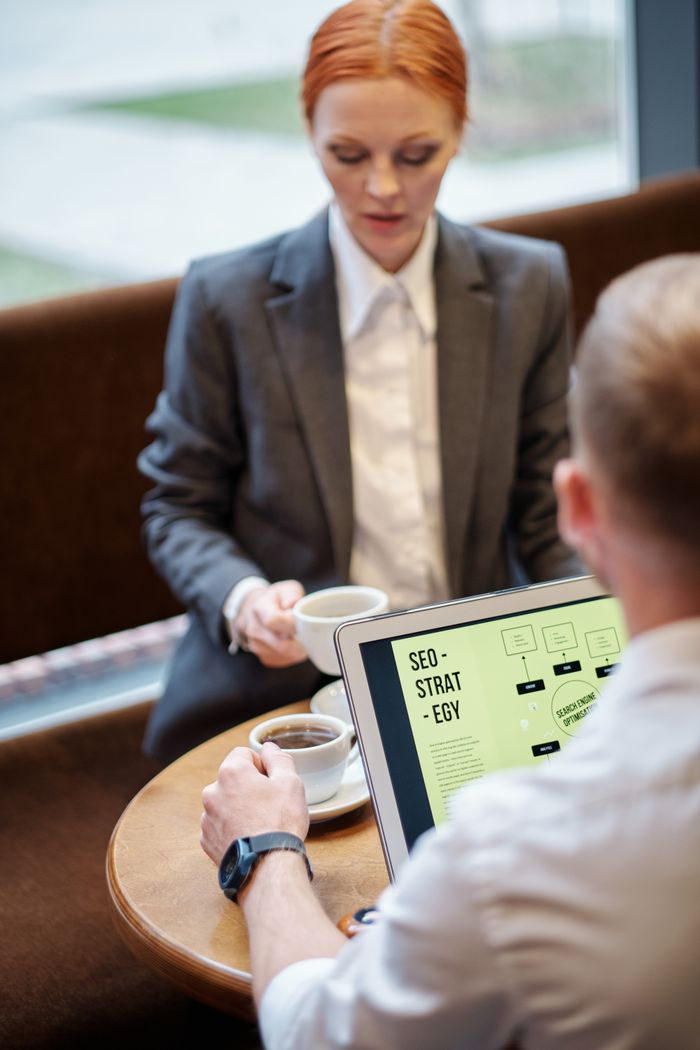 A professional café meeting with a laptop displaying an SEO strategy. Well suited to business concepts.